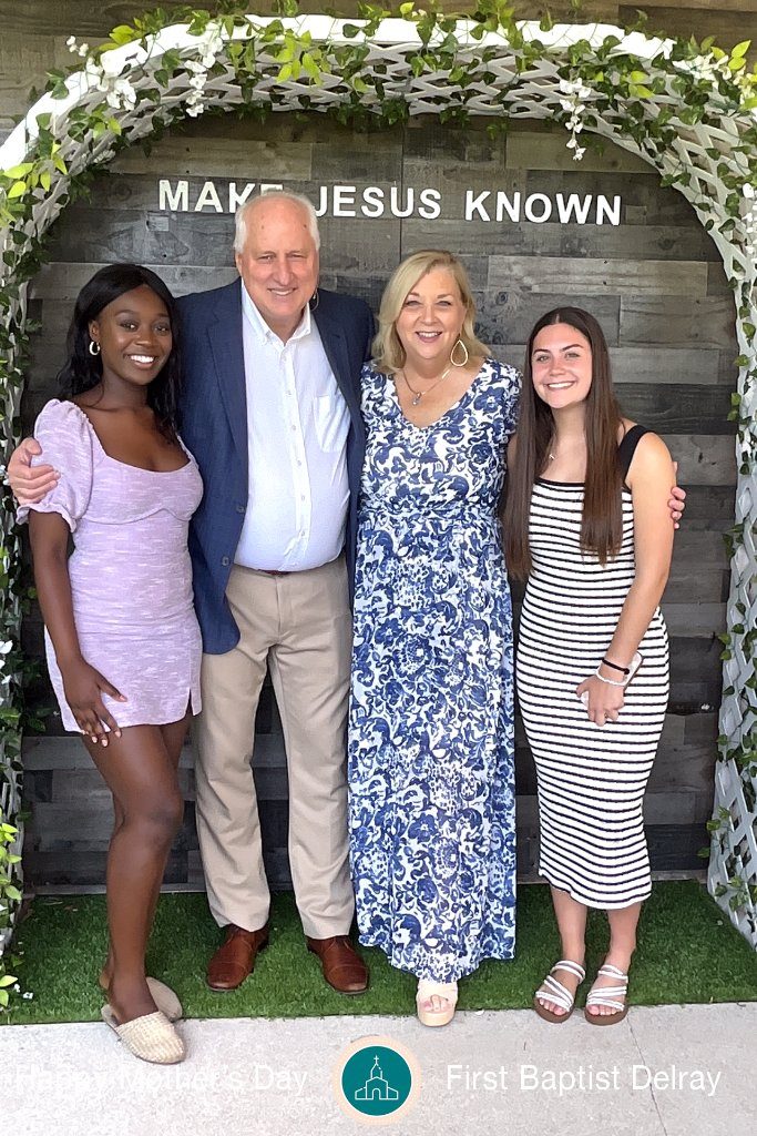 Family posing under a greenery arch at a community event